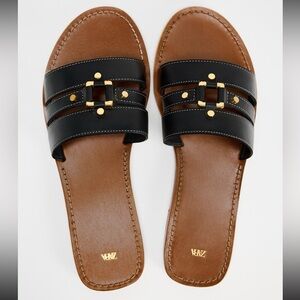 Black leather flat sandal with gold metal detail